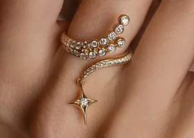 The reference picture: a gold bypass ring with pave strands, a cluster of bezel stones and a dangling star